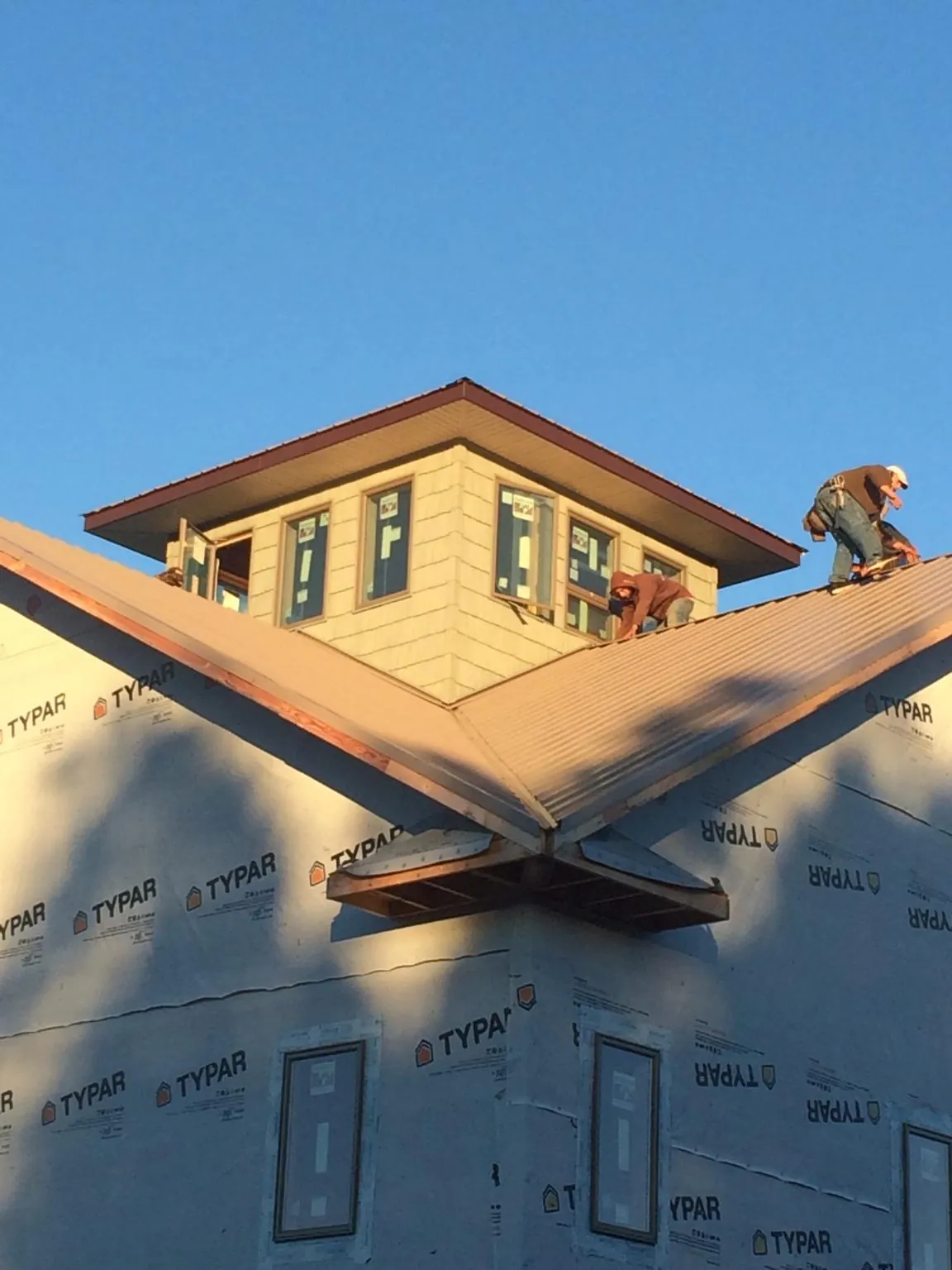 Roofers working around a rooftop cupola on a new metal roof at sunset — Roof Waterproofing in Bluffton by Roofing Brothers